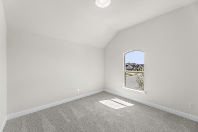 carpeted empty room with lofted ceiling