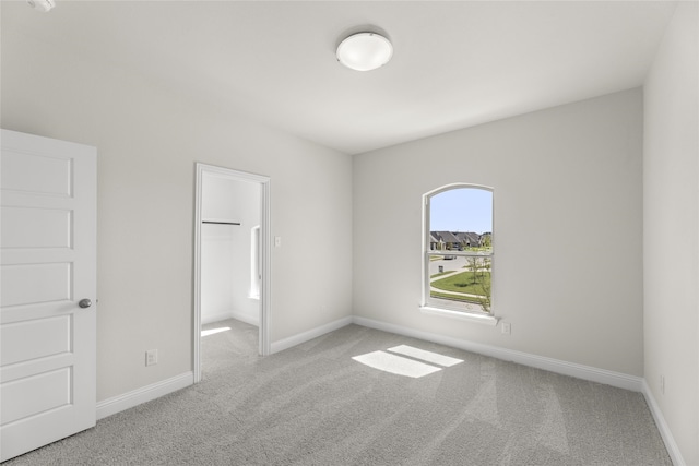 unfurnished bedroom featuring light carpet, a spacious closet, and a closet