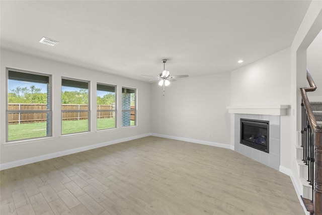 unfurnished living room with ceiling fan, light hardwood / wood-style flooring, and a tiled fireplace