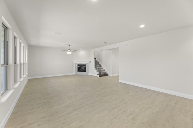 unfurnished living room with ceiling fan, a wealth of natural light, and light hardwood / wood-style floors