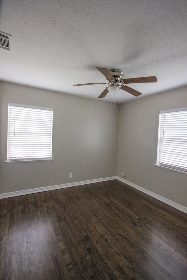 spare room featuring plenty of natural light, ceiling fan, dark hardwood / wood-style flooring, and a textured ceiling