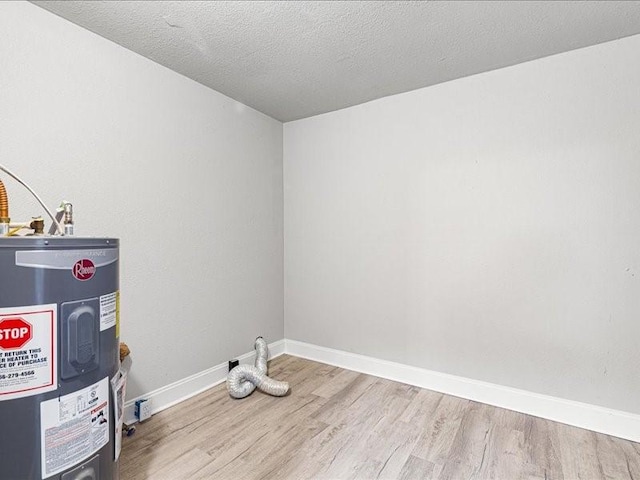 laundry area featuring water heater, a textured ceiling, and light hardwood / wood-style floors