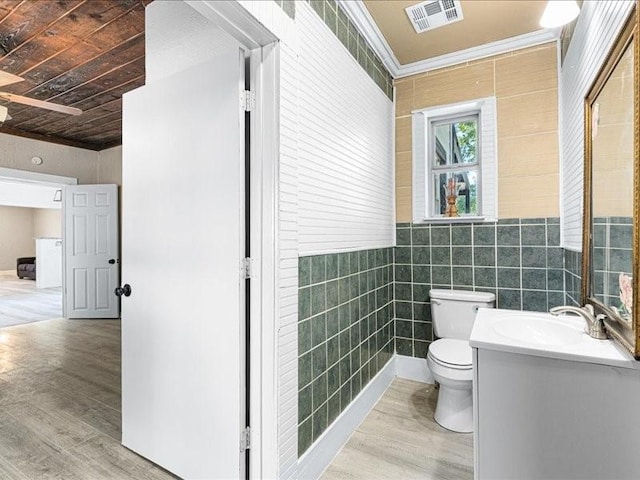 bathroom featuring toilet, crown molding, tile walls, vanity, and hardwood / wood-style flooring