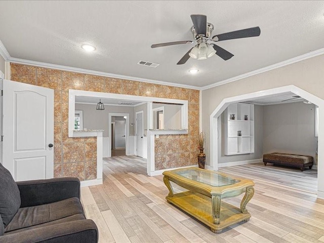 living room featuring crown molding, ceiling fan, hardwood / wood-style floors, and a textured ceiling