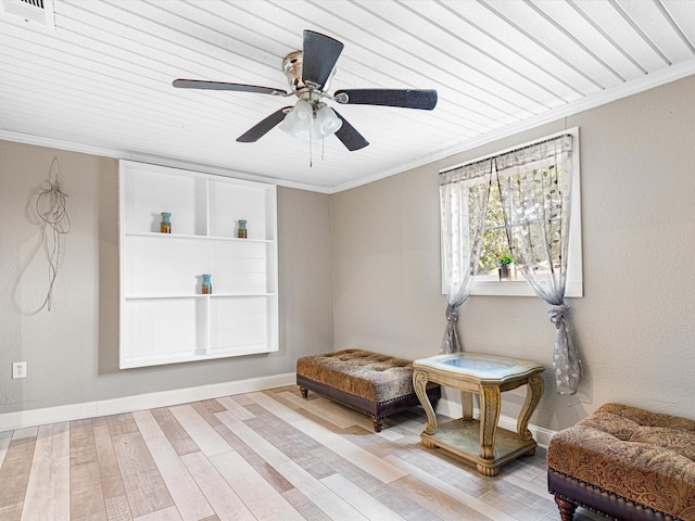 living area featuring crown molding and light hardwood / wood-style flooring