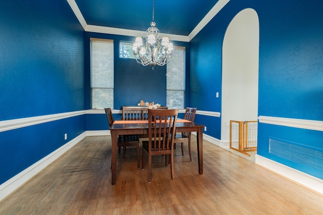 dining area featuring a notable chandelier, hardwood / wood-style flooring, and ornamental molding