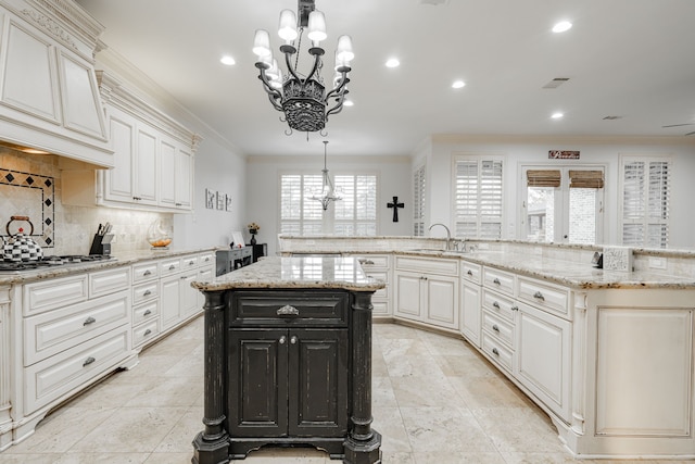 kitchen featuring stainless steel gas cooktop, a large island, decorative light fixtures, an inviting chandelier, and crown molding