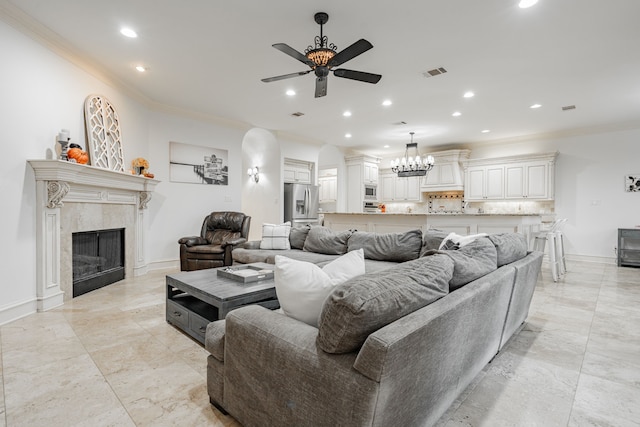 living room featuring ceiling fan with notable chandelier, a fireplace, and ornamental molding