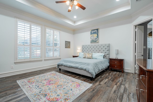 bedroom featuring ceiling fan, a tray ceiling, dark wood-type flooring, and ornamental molding