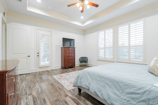 bedroom featuring light wood-type flooring, ceiling fan, crown molding, a tray ceiling, and access to exterior