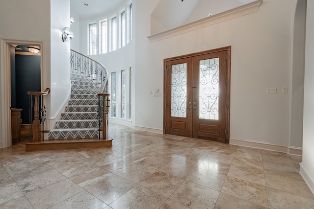 entryway with french doors, ornamental molding, and a high ceiling