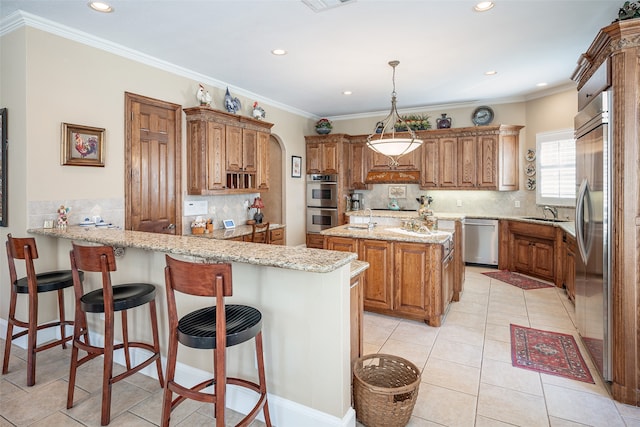 kitchen featuring appliances with stainless steel finishes, hanging light fixtures, decorative backsplash, light stone counters, and kitchen peninsula