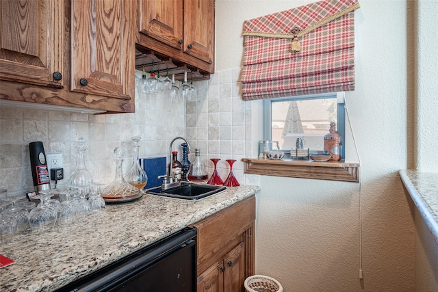 kitchen with decorative backsplash, dishwasher, light stone countertops, and sink