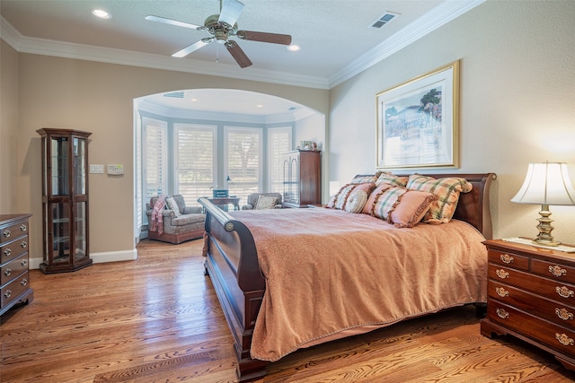 bedroom with wood-type flooring, crown molding, and ceiling fan