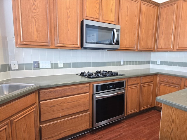 kitchen featuring appliances with stainless steel finishes, backsplash, and dark hardwood / wood-style flooring