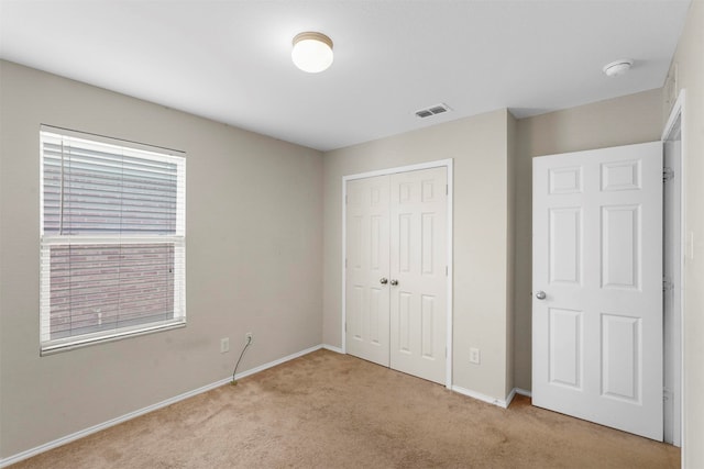 unfurnished bedroom with light carpet and a closet