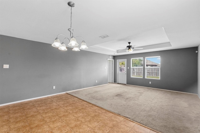 spare room with ceiling fan with notable chandelier, a tray ceiling, and light colored carpet