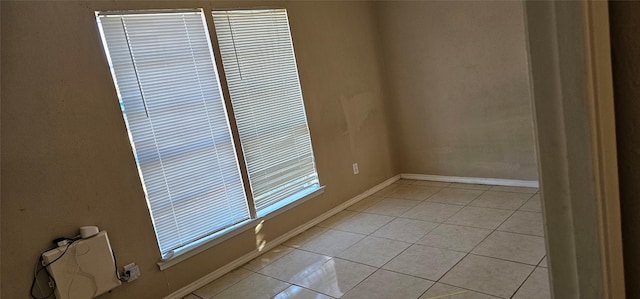 spare room with baseboards and light tile patterned floors