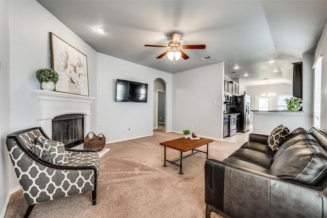 carpeted living room with ceiling fan with notable chandelier