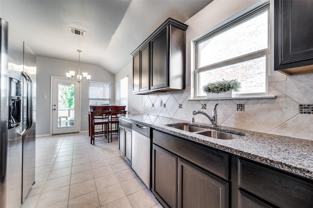 kitchen with backsplash, vaulted ceiling, stainless steel appliances, a chandelier, and sink