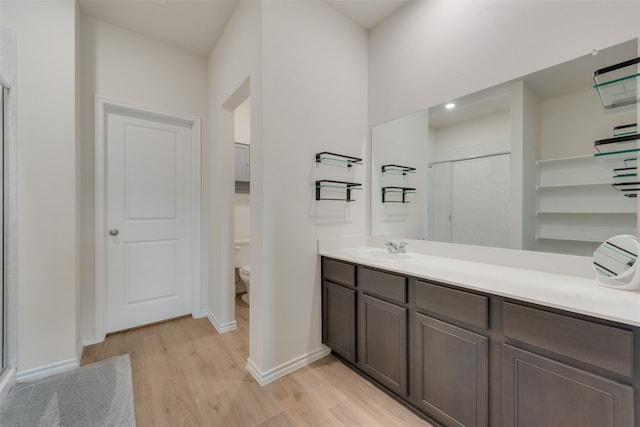 bathroom featuring vanity, toilet, wood-type flooring, and an enclosed shower