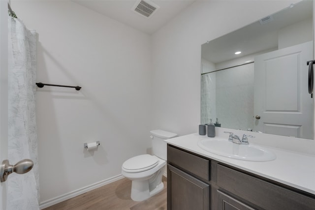 bathroom featuring wood-type flooring, toilet, walk in shower, and vanity