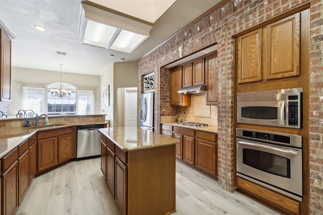 kitchen featuring sink, a center island, an inviting chandelier, light hardwood / wood-style flooring, and appliances with stainless steel finishes