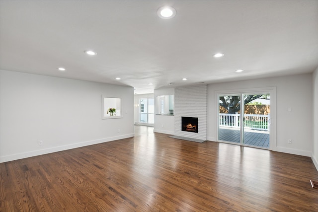 unfurnished living room featuring dark wood-type flooring and a fireplace