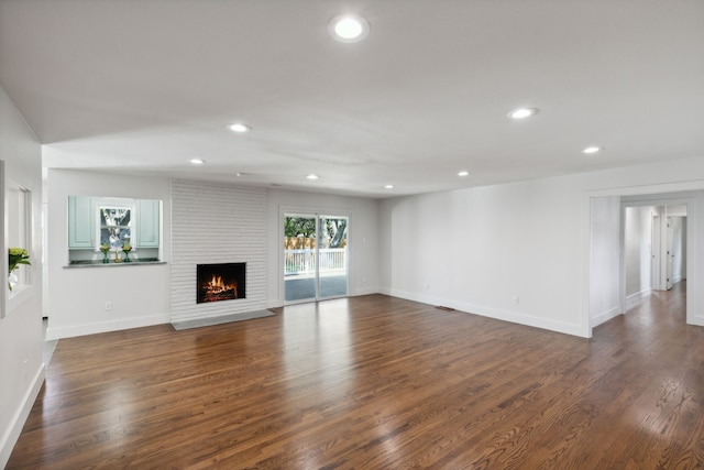 unfurnished living room with dark wood-type flooring and a fireplace