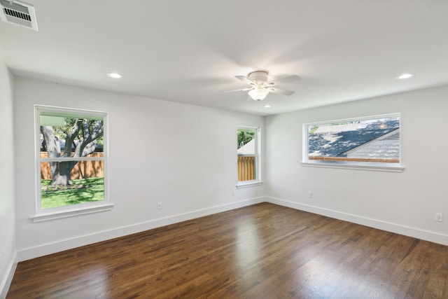 spare room with ceiling fan, a wealth of natural light, and dark hardwood / wood-style floors