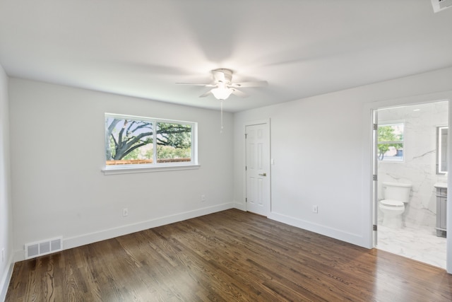 empty room with dark wood-type flooring, a wealth of natural light, and ceiling fan