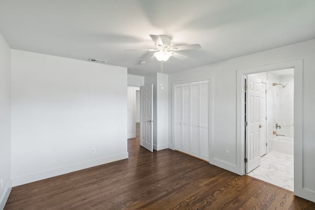 unfurnished bedroom featuring ceiling fan, ensuite bathroom, and dark hardwood / wood-style flooring