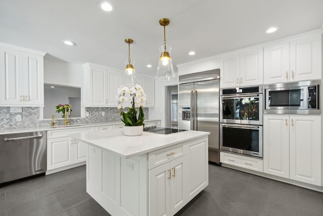 kitchen with built in appliances, tasteful backsplash, a center island, hanging light fixtures, and white cabinetry