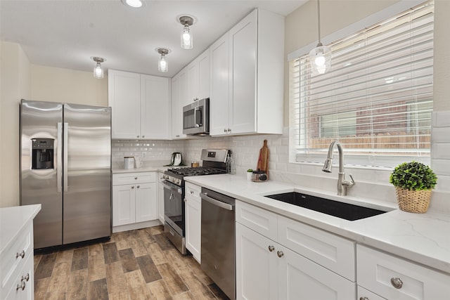 kitchen with pendant lighting, white cabinetry, stainless steel appliances, and sink