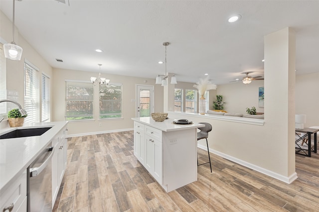 kitchen with white cabinets, ceiling fan with notable chandelier, sink, a breakfast bar area, and stainless steel dishwasher