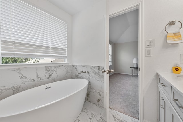 bathroom with vanity, a bath, and vaulted ceiling