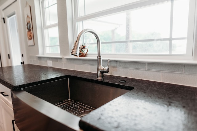 room details featuring backsplash, sink, and white cabinetry