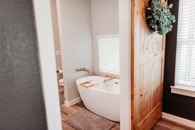 bathroom with hardwood / wood-style floors, toilet, and a tub