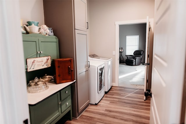 laundry area with cabinets, light wood-type flooring, and washer and clothes dryer