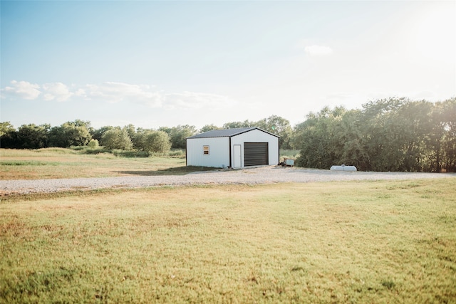 view of yard featuring an outdoor structure, a garage, and a rural view