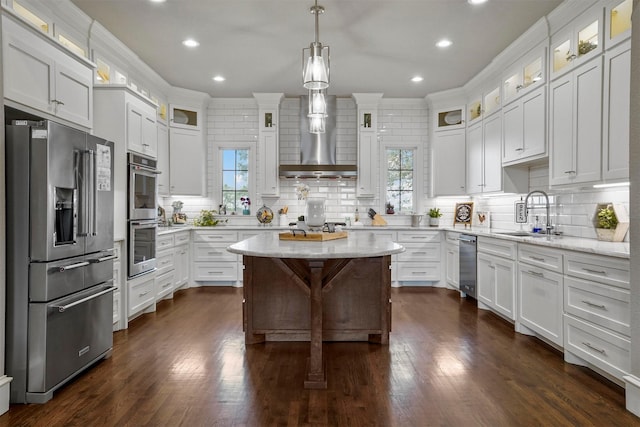 kitchen featuring stainless steel appliances, white cabinetry, a kitchen island, and sink