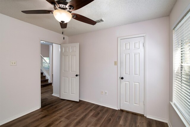 unfurnished bedroom featuring ceiling fan, dark wood-type flooring, and a textured ceiling