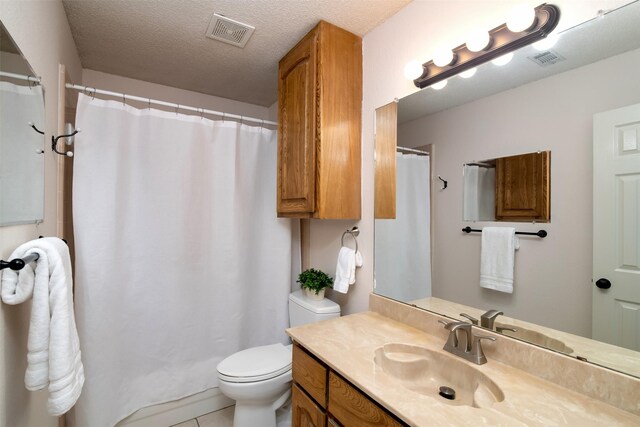 bathroom featuring curtained shower, vanity, a textured ceiling, tile patterned flooring, and toilet