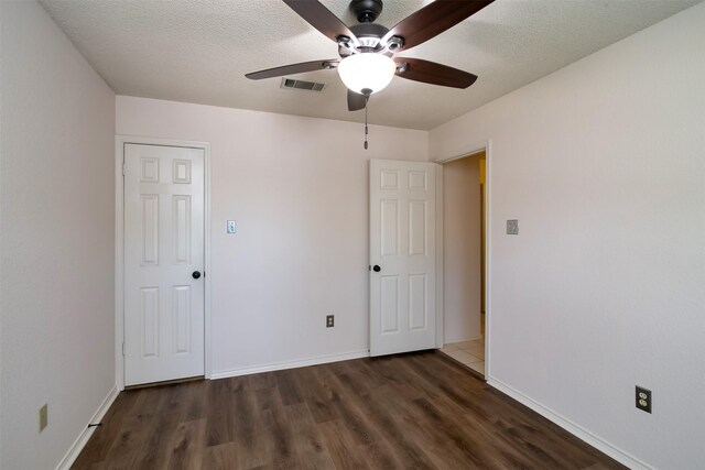 unfurnished bedroom featuring ceiling fan, dark wood-type flooring, and a textured ceiling