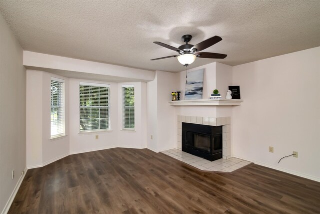 unfurnished living room with ceiling fan, a tiled fireplace, wood-type flooring, and plenty of natural light