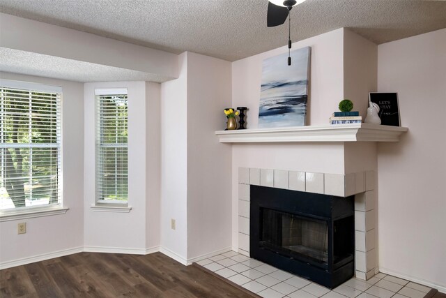 interior space with a wealth of natural light, light hardwood / wood-style floors, a tile fireplace, and a textured ceiling