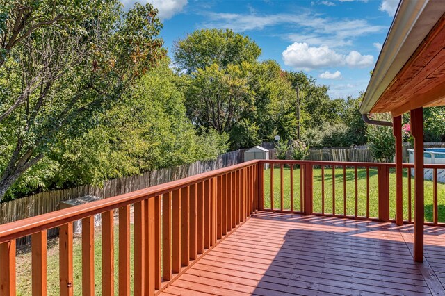 wooden deck featuring a storage unit and a yard