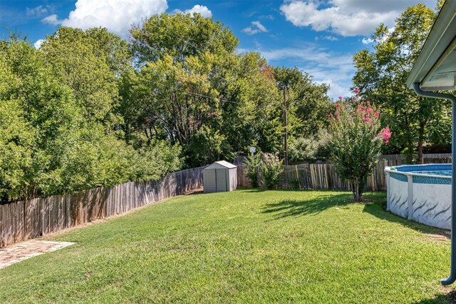 view of yard featuring a fenced in pool and a shed