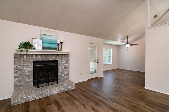 unfurnished living room featuring ceiling fan, lofted ceiling, a brick fireplace, a textured ceiling, and dark hardwood / wood-style floors