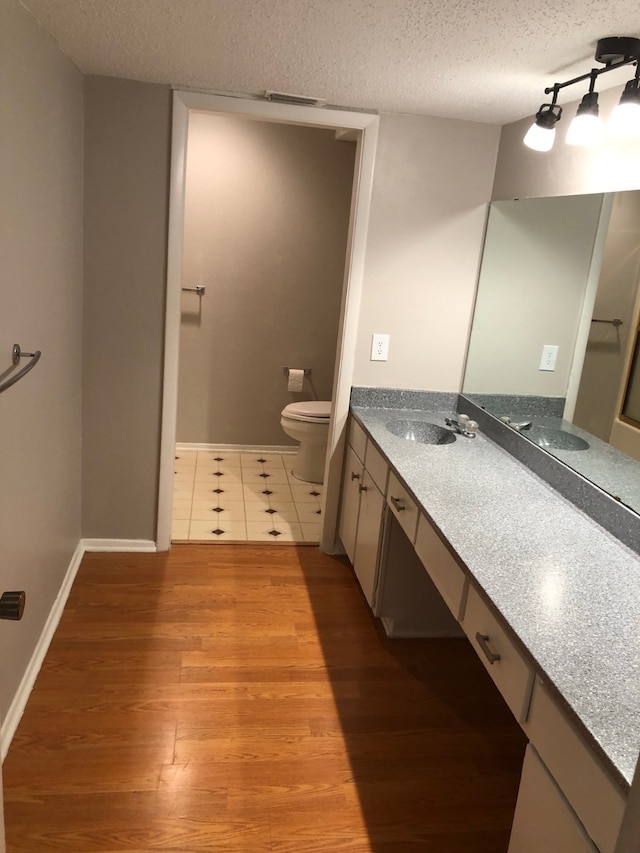 bathroom with vanity, hardwood / wood-style flooring, toilet, and a textured ceiling